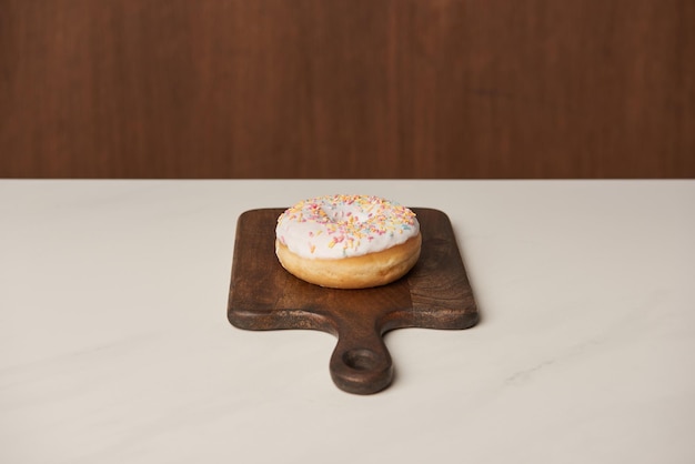 Delicious glazed donut on wooden cutting board