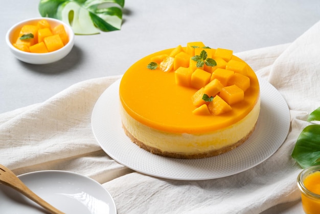 Delicious glazed mango no baked cheese cake with fresh diced mango pulp topping on bright table background