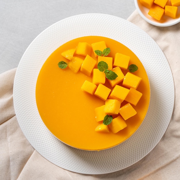 Delicious glazed mango no baked cheese cake with fresh diced mango pulp topping on bright table background