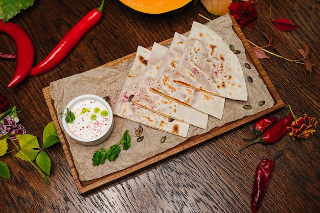 Delicious gourmet flat bread kutabs with herbs and cheese on a wooden board with sauce