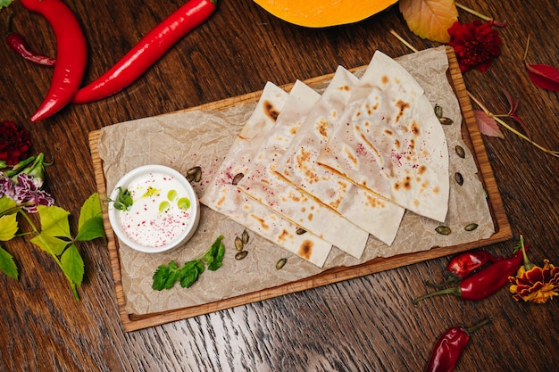 Delicious gourmet flat bread kutabs with herbs and cheese on a wooden board with sauce