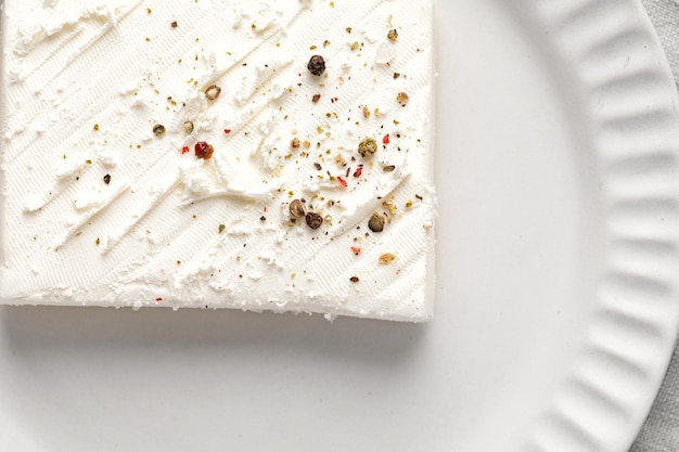 Delicious greek feta cheese with pepper and spices Clean White plate Close up