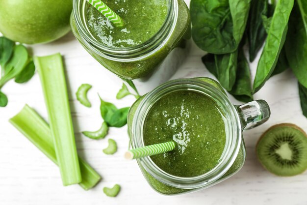 Delicious green juice and fresh ingredients on white table flat lay