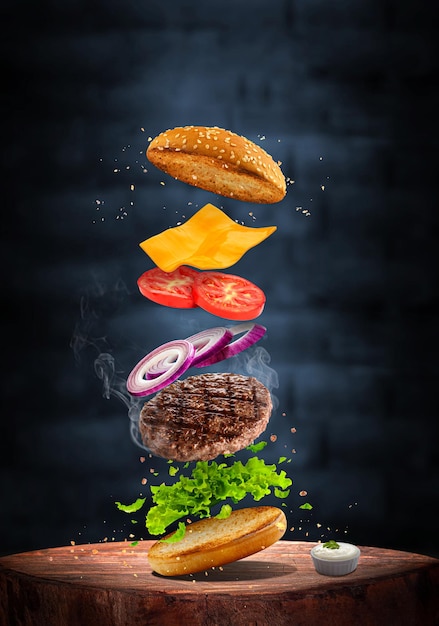 вкусный бургер из говядины на гриле с летающими ингредиентами, изолированными на темном фоне. креативный дизайн