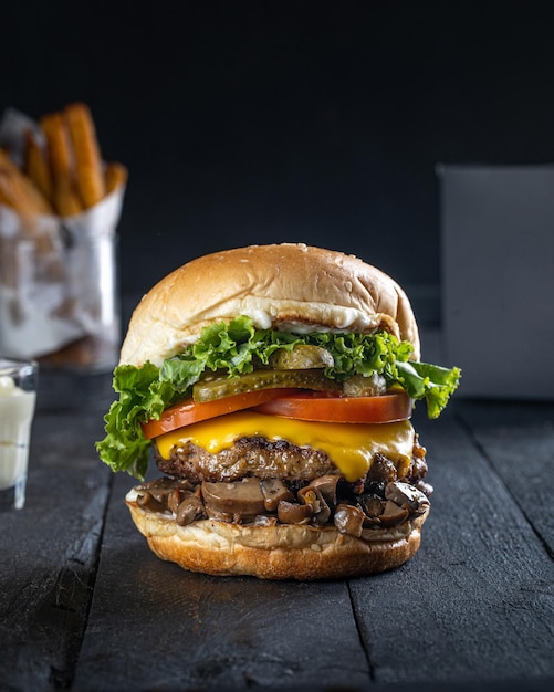 Delicious grilled burger on table side view dark background