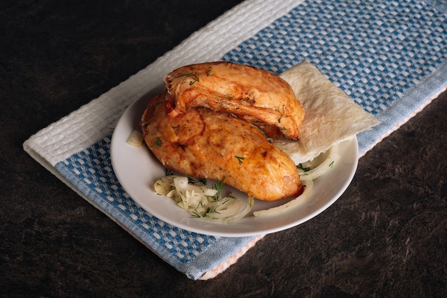 Delicious grilled chicken breasts on a plate on the dark background