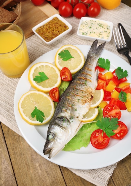 Delicious grilled fish on plate on table closeup