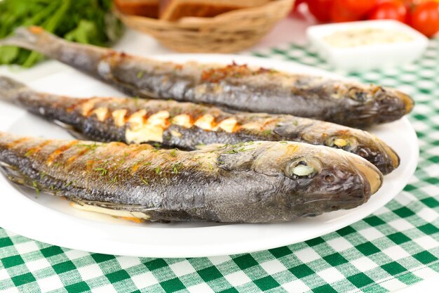 Delicious grilled fish on plate on table closeup