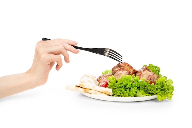 Delicious grilled meat with vegetable on white plate isolated on white background Meat in female hand on the fork