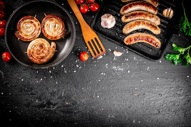 Delicious grilled sausages in a frying pan with fresh tomatoes