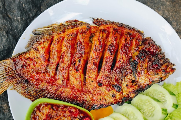 Deliziosa tilapia alla griglia nila bakar dall'indonesia con verdure tempeh di riso e salsa di peperoncino nel piatto