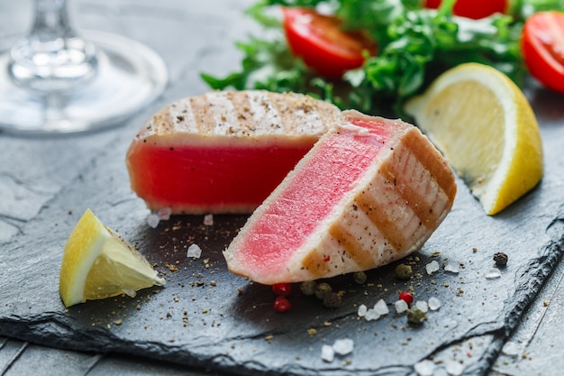 Photo delicious grilled tuna with pepper, lemon and salad of greens and tomatoes