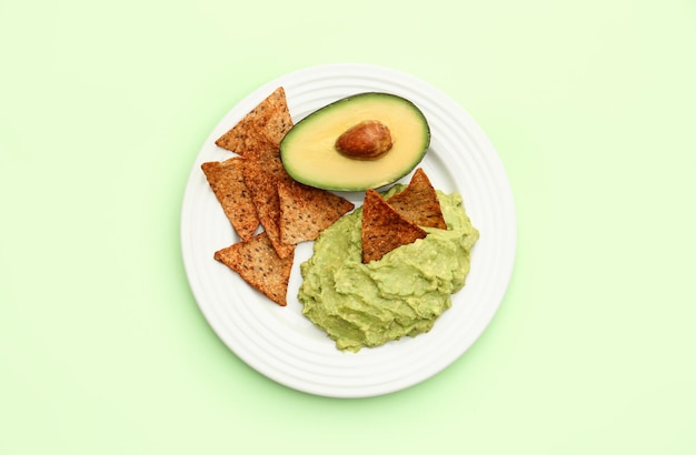 Delicious guacamole avocado and nachos on light green background top view