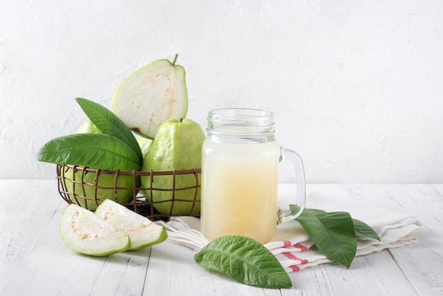 Delicious guava fruit with fresh juice on bright white wooden table background