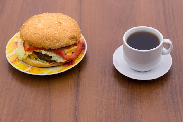 木製のテーブルの上で美味しいハンバーガーとカップのコーヒー