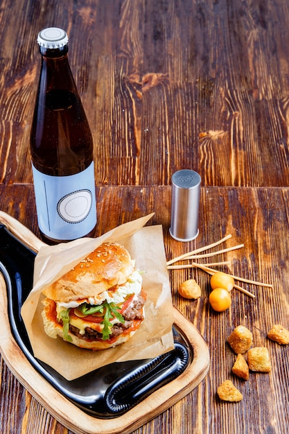 Delicious hamburger, snacks and beer on a wooden table