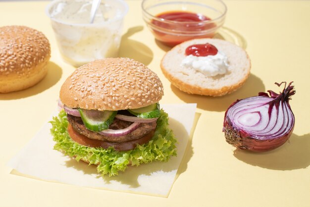 Delicious hamburger on a white plate on a wooden and sauces