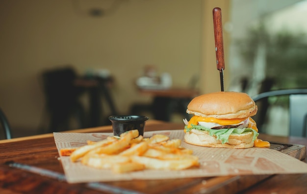 Фото Вкусный гамбургер с картошкой фри на деревянном столе. сырный гамбург с картошкою фри, подаваемый на деревяnном столе с копировальным пространством.