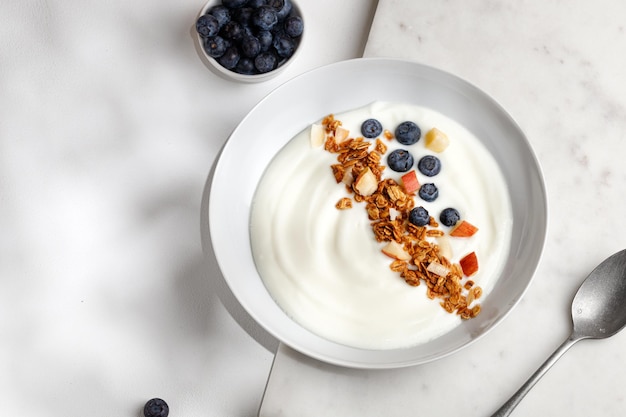 Delicious healthy breakfast bowl with white yogurt fresh blueberries with granola or muesli Top view