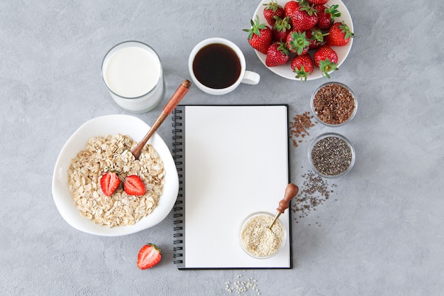 Delicious and healthy breakfast ingredients: oatmeal, milk, seeds, strawberries