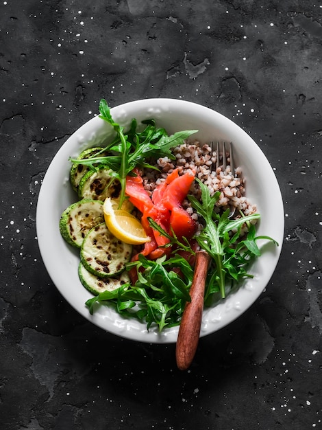 Delicious healthy breakfast lunch snack buckwheat lightly salted salmon squash arugula on a dark background top view