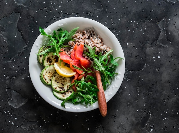 Delicious healthy breakfast lunch snack buckwheat lightly salted salmon squash arugula on a dark background top view