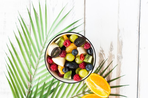 Delicious healthy breakfast with a mix of chopped fruits and berries in a bowl. top view.