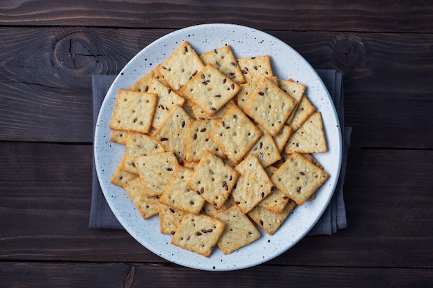 Delicious healthy cookies crackers with flax seeds and sesame seeds on a plate. Background of a healthy snack food, dark rustic wooden table. Copy space.