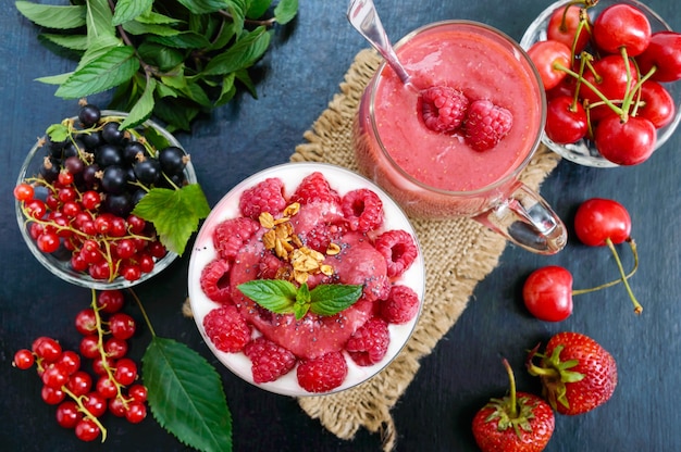 Delicious healthy dessert: yoghurt, fresh berries, granola, raspberry sauce on a black.