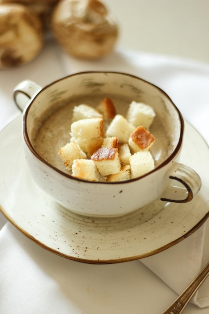 Delicious and healthy homemade mushroom cream soup with croutons in a plate on the table