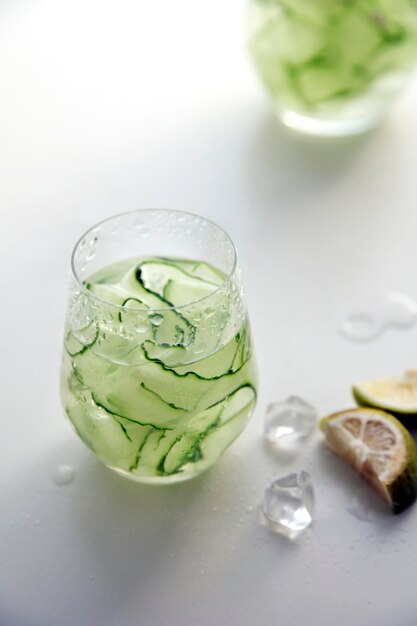 Delicious healthy and nutritious cucumber water in the transparent glass on the white table