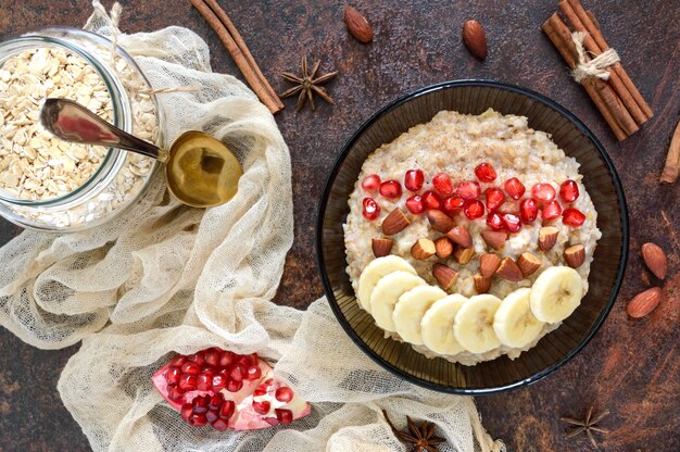 Farina d'avena deliziosa e salutare con banana, semi di melograno, mandorle e cannella. colazione salutare. cibo fitness. nutrizione appropriata. disposizione piatta. vista dall'alto.