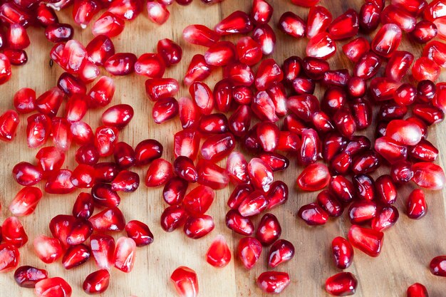 Delicious and healthy pomegranate divided into several parts with red seeds, red and ripe fruit pomegranate with red grains, fresh pomegranate closeup