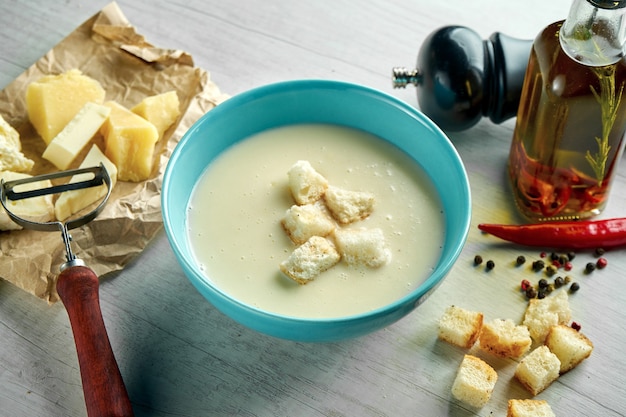 Delicious and hearty cream cheese soup with croutons in a blue bowl on a wooden table. restaurant food