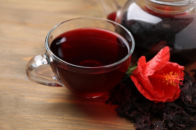 Delicious hibiscus tea and flower on wooden table closeup