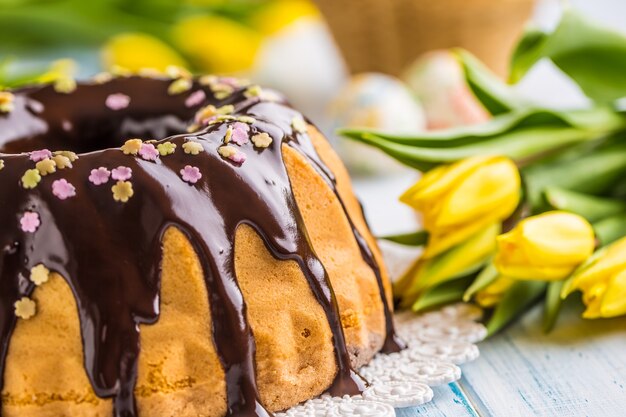 Delicious holiday slovak and czech cake babovka with chocolate glaze. Easter decorations - spring tulips and eggs.