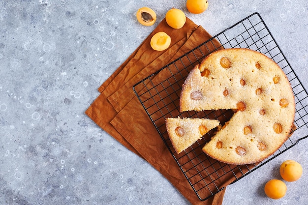 Deliziosa torta di albicocche fatta in casa con albicocche fresche sulla griglia di cottura su sfondo grigio