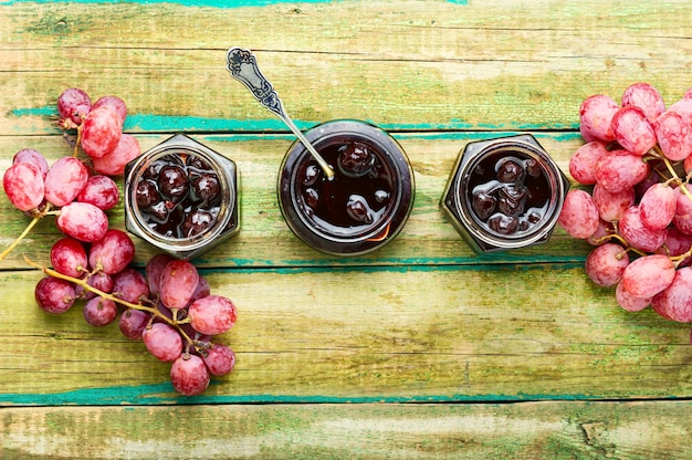 Delicious homemade autumn grape jam on wooden table