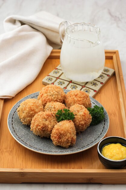 Delicious Homemade Brulee Bomb Made from Flour, Cheese, Milk Coated with Bread Crumb. Bitterballen Look a Like, Served on White Plate, Wooden Background with Parsley as Garnish