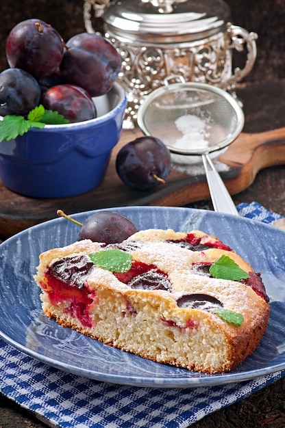 Photo delicious homemade cake with plums on a wooden surface