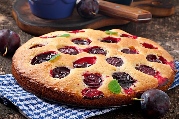 Delicious homemade cake with plums on a wooden