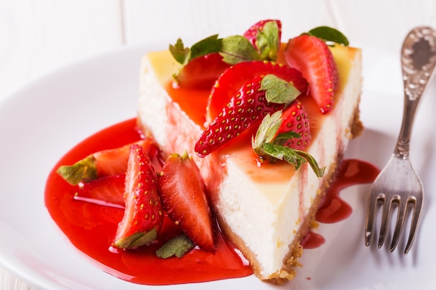 Delicious homemade cheesecake with strawberries  on  white wooden table.