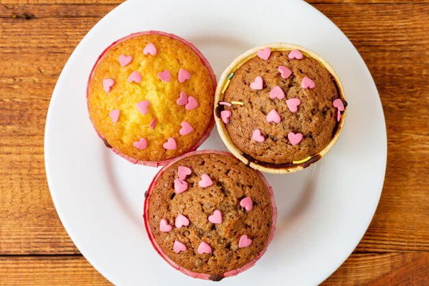 Delicious homemade colorful cupcakes with heart-shaped confectionery close up