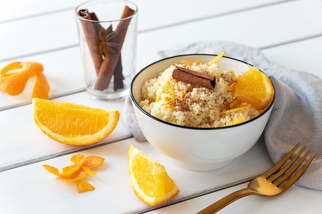 Delicious homemade couscous with oranges and cinnamon on rustic wooden background. Tasty vegan food.