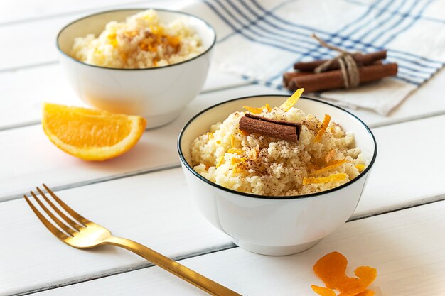 Delicious homemade couscous with oranges and cinnamon on rustic wooden background. Tasty vegan food.