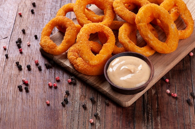 Delicious homemade crunchy fried onion rings with spicy sauce. Copy space