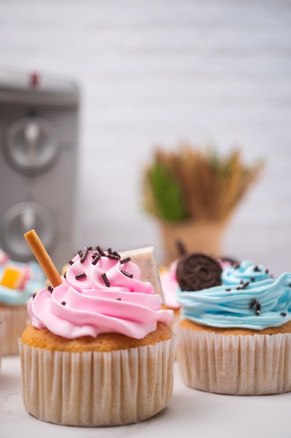 Deliziosi cupcakes fatti in casa con crema colorata e guarnire con caramelle e biscotti al cioccolato.