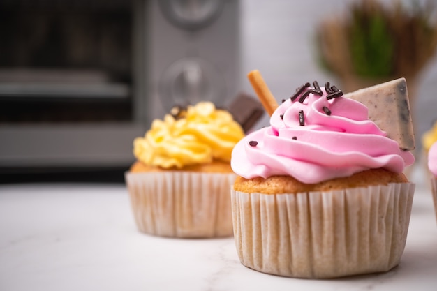 Delicious homemade cupcakes with colorful cream and topping with candy