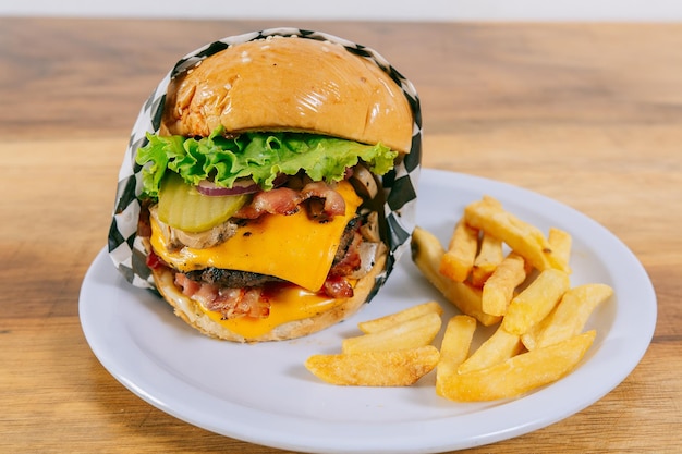 Delicious homemade hamburger on a plate on a wooden table Big cheeseburger with french fries served on wooden table