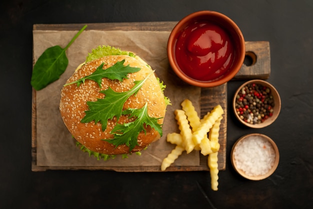 delicious homemade hamburger with beef, lettuce, cheese, cucumber and french fries on stone background
